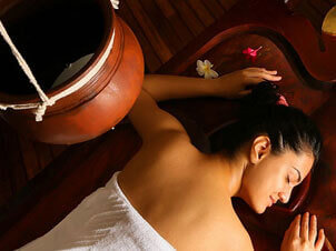 women laying on bed taking shirodhara massage